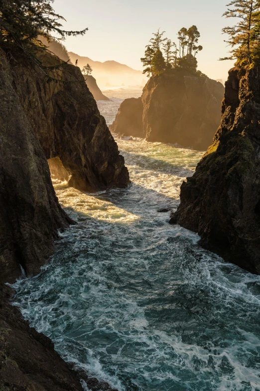 the sun shines on the rocky waters near the shore