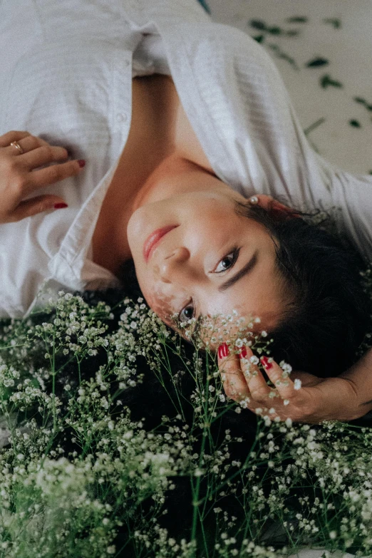 a woman laying on her side next to a bunch of flowers