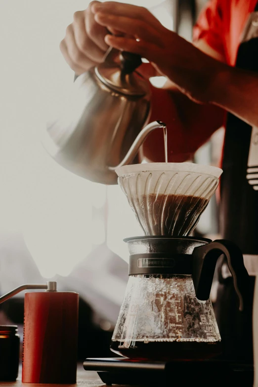 someone pours coffee into a glass cup