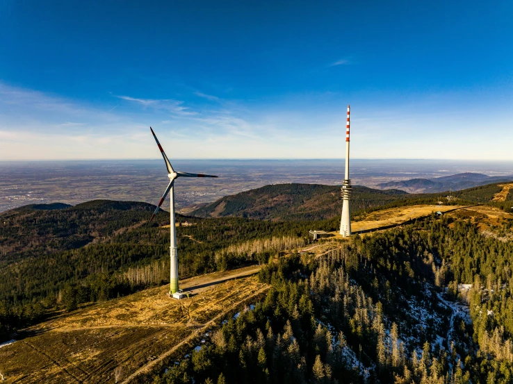 three wind turbine generators overlooking the hills with trees on top