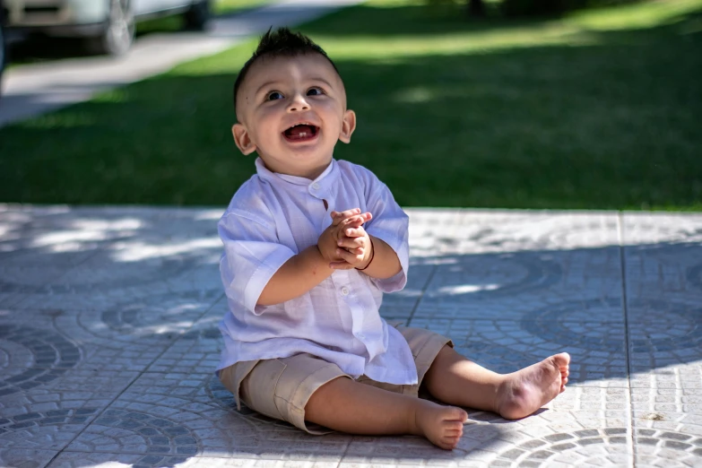 a little boy sitting on the ground with his hands crossed