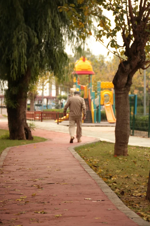 a man walking on the sidewalk in the park