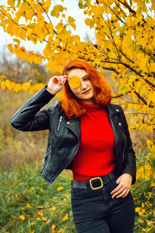 a beautiful young lady holding an orange up to her eye