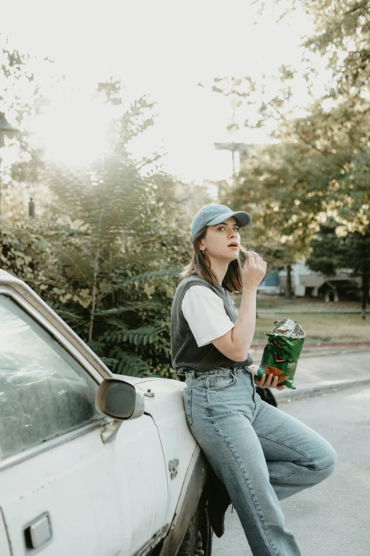 a woman sitting on the hood of a car smoking