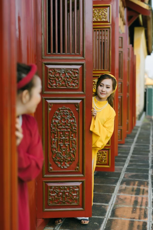 little girl dressed up in traditional dress standing by red doors