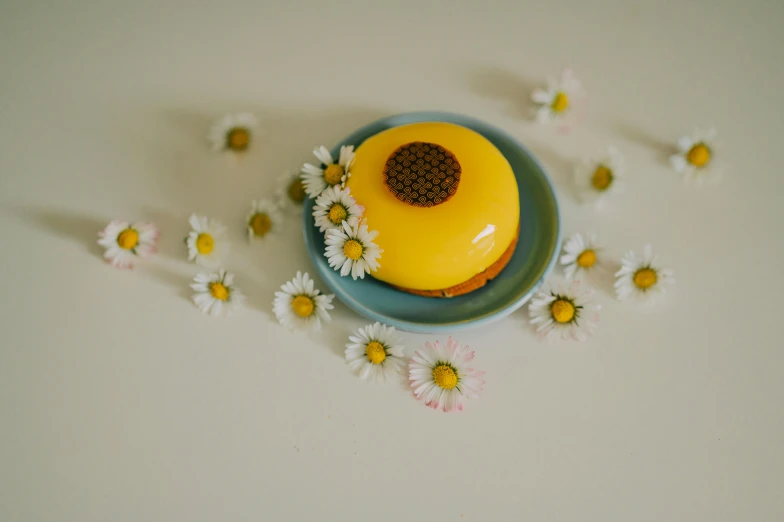 the yellow frosted cake is surrounded by small daisies