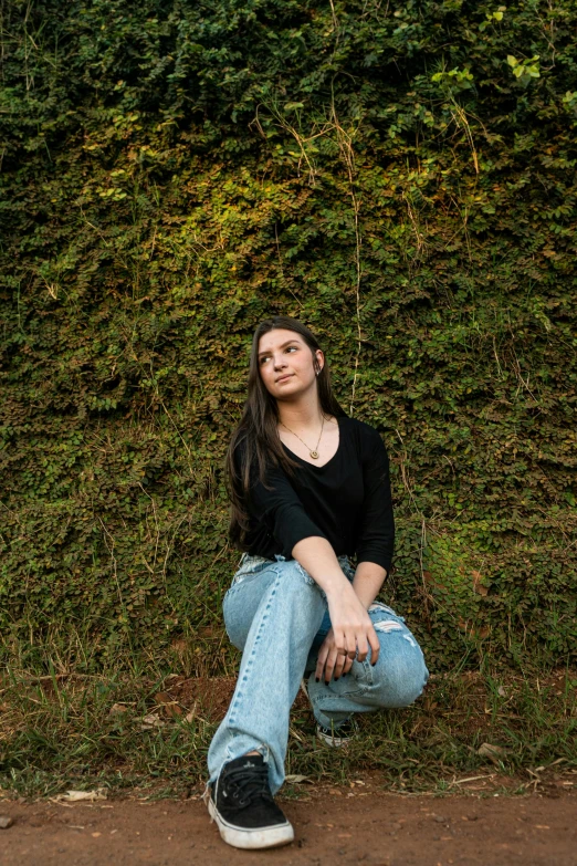 a girl sitting on a pavement in front of a wall