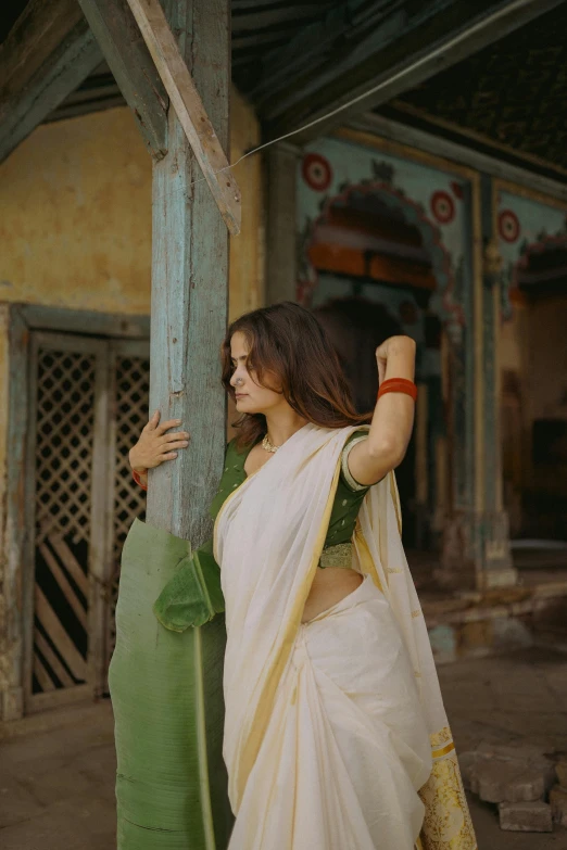 a beautiful young woman leaning against a pillar