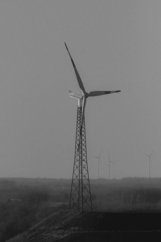 a wind turbine sits on top of a hill in front of fog