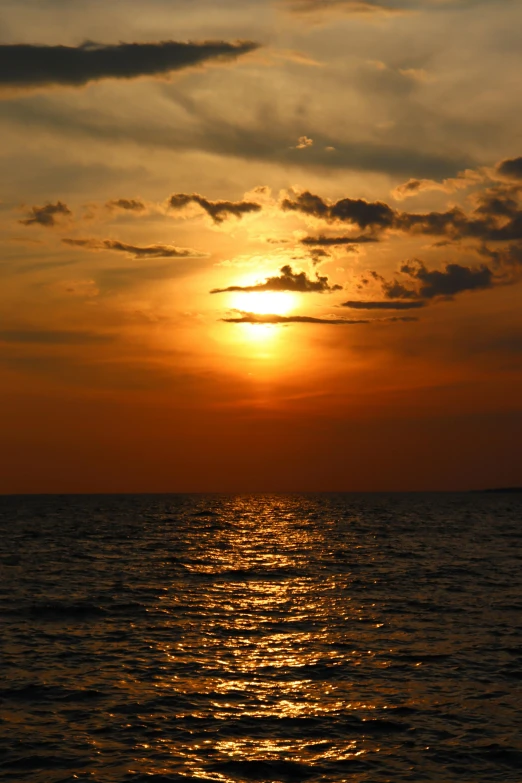 a sailboat sails across the waters of a sunset