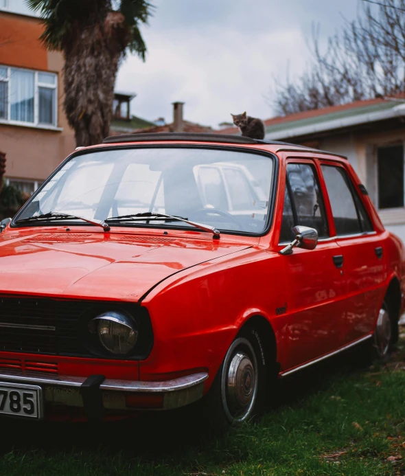 an old car parked on grass near house