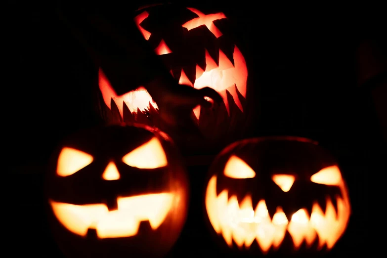 three carved pumpkins lit up with their mouths