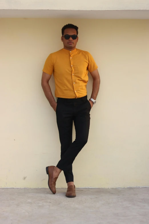 a man in a yellow shirt standing in front of a white wall