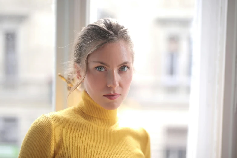 a woman wearing a yellow sweater looking at the camera