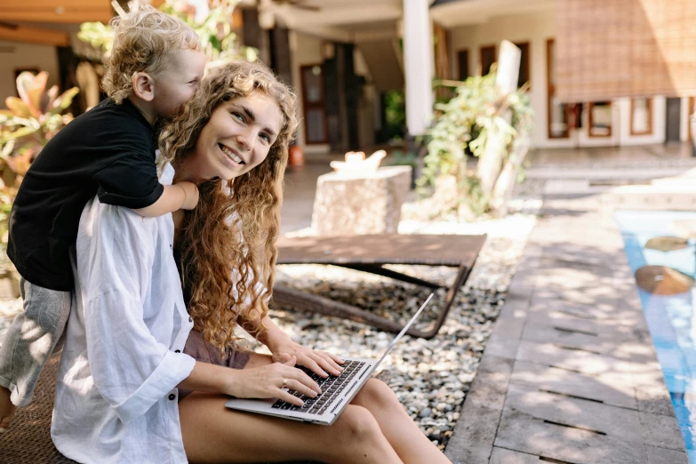 a woman holding her son while they work on their laptop