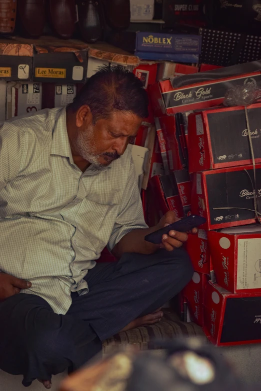 a man is sitting in a store, looking at his cellphone