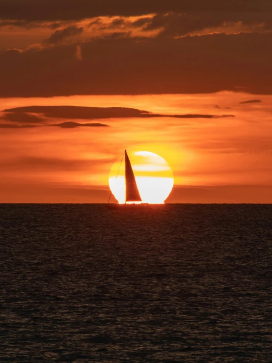 a sailboat is silhouetted by the sun setting