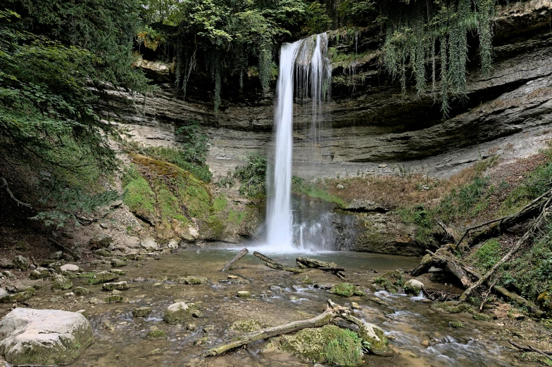 a small waterfall with rocks and trees near by