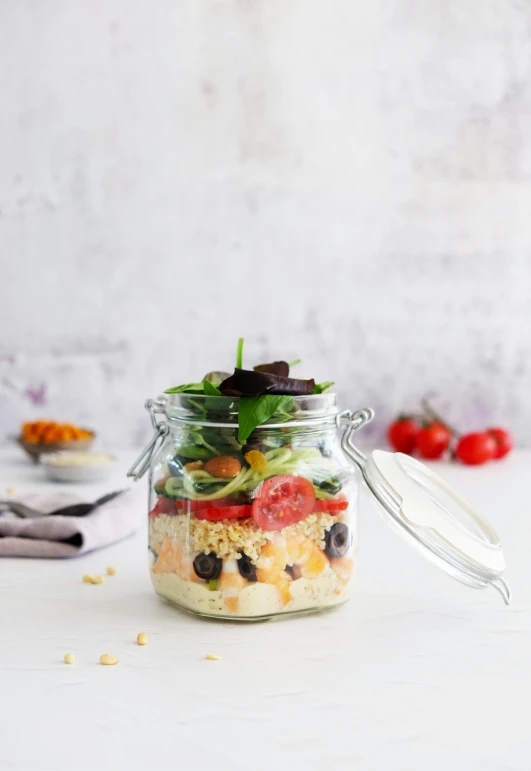 a glass jar of food with vegetables inside