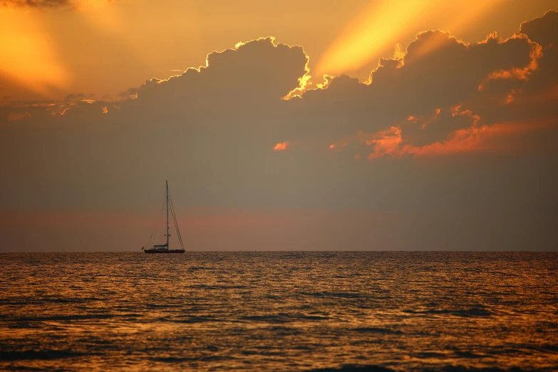 an orange sun rises over the ocean as a boat travels in the water