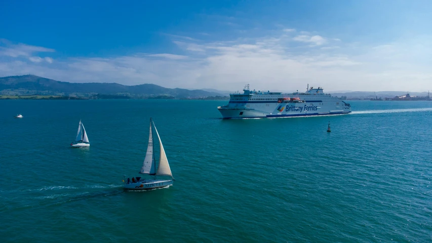 several small sailboats traveling in large blue water