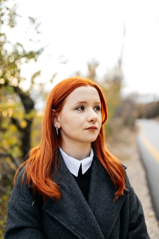 a woman in a black coat staring off into the distance