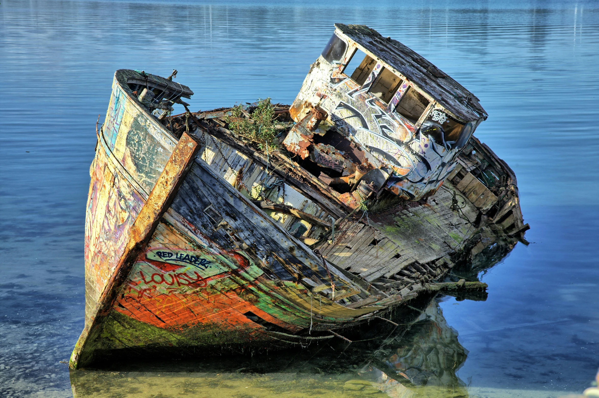 an old boat sitting in the middle of a lake