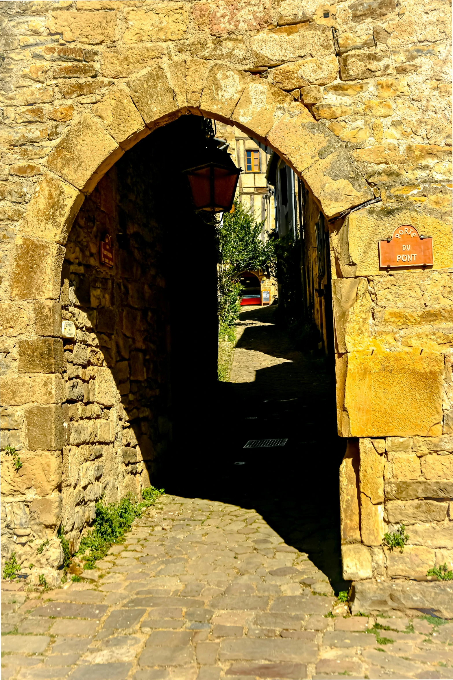 an archway leading to a street that has plants growing out of it