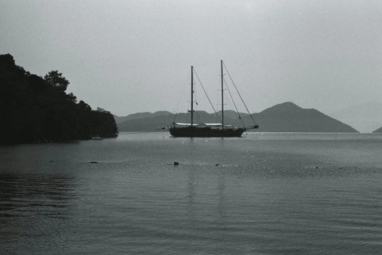 a sail boat on water with mountains in the distance