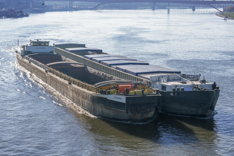 two barges in the water one with several cargos