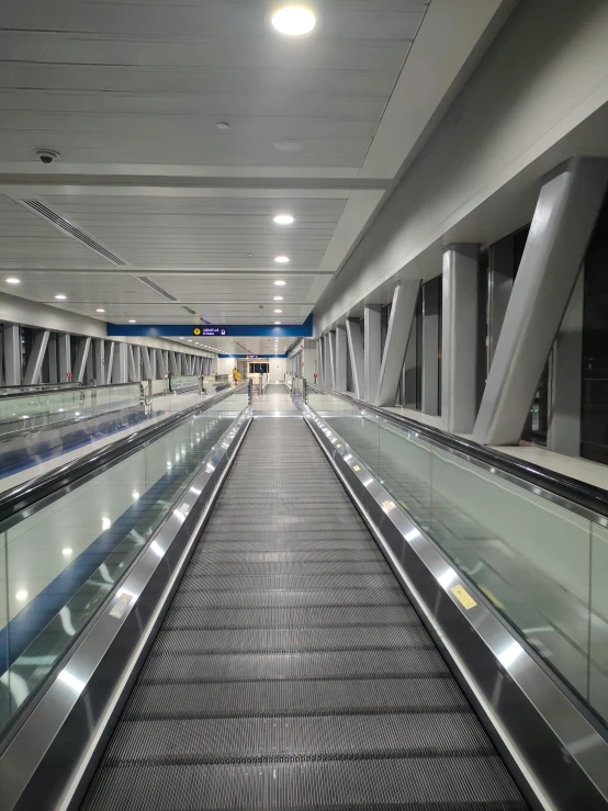 an escalator at an airport with a few people riding down