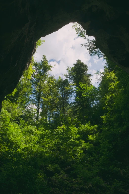 a po taken from under an open natural stone archway looking out into the trees