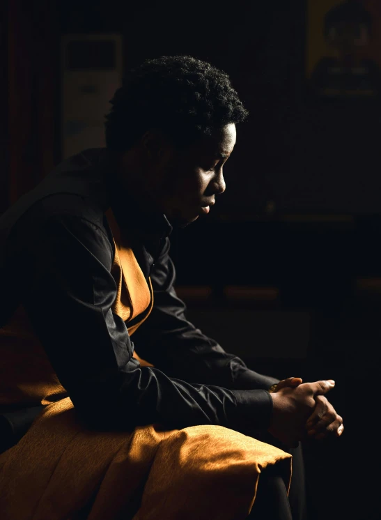 black man with hand on chair in dark room