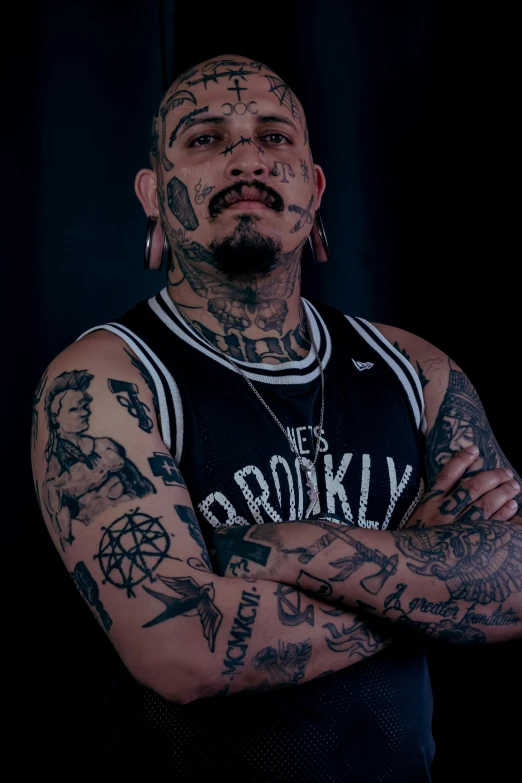 tattooed man wearing hoop earrings and jersey with armbands