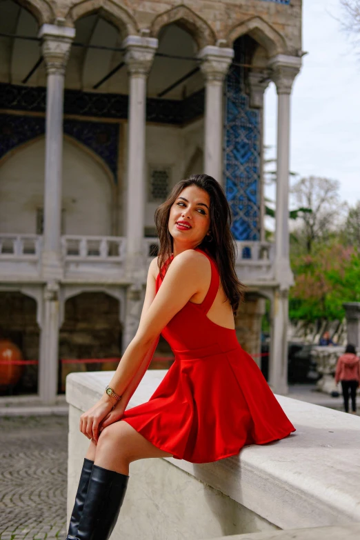 a girl in red dress posing on white wall