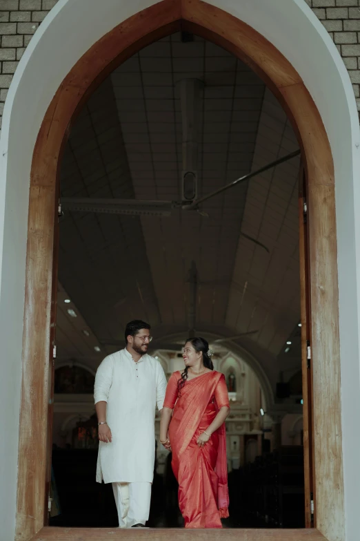 a man and woman in orange outfits standing at an entrance