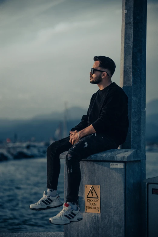 a man in black is sitting on a cement ledge