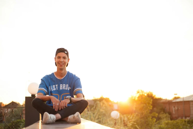 a man sitting on a wooden post in front of the sunset