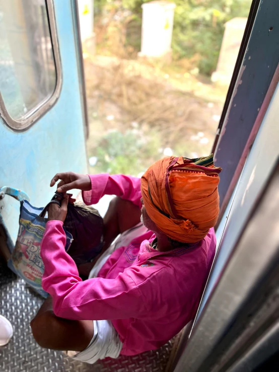 a woman wearing an orange hat sitting on a train