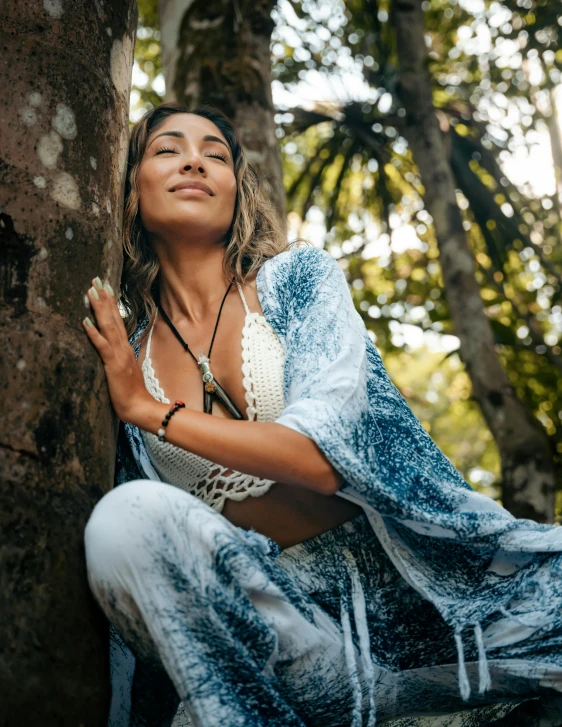 a woman in a long dress kneeling next to a tree