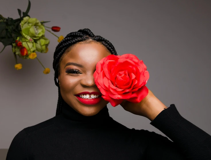 smiling woman holding a large flower in her left hand