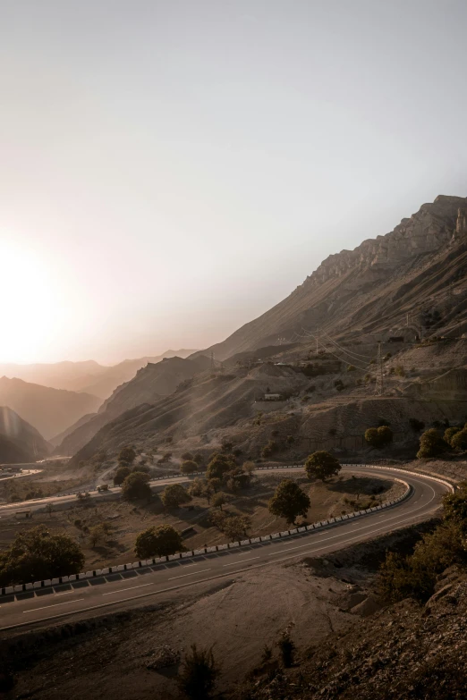 a winding road in the mountains with light colored skies