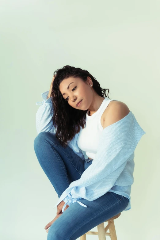 a woman sitting on a stool in denim