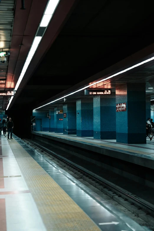 a passenger subway station with people waiting on the platform