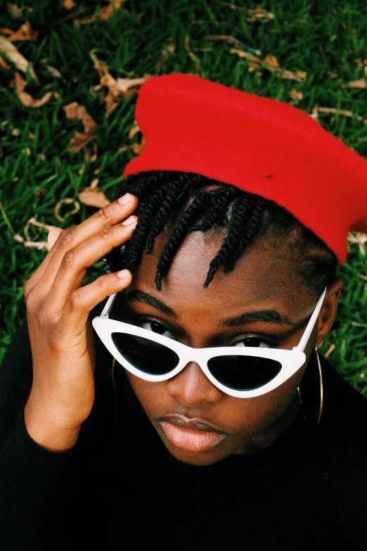 a close - up view of the front of a woman with short hair wearing sunglasses and a red cap