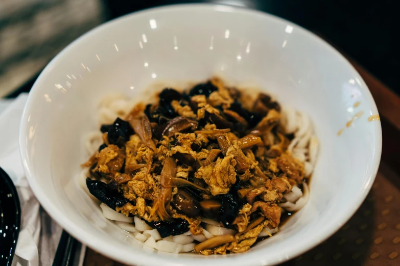 a bowl filled with meat and noodles sitting on a table