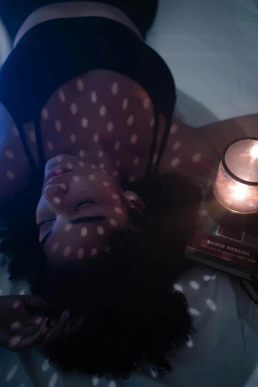 a girl is laying down with a book and a light on the table