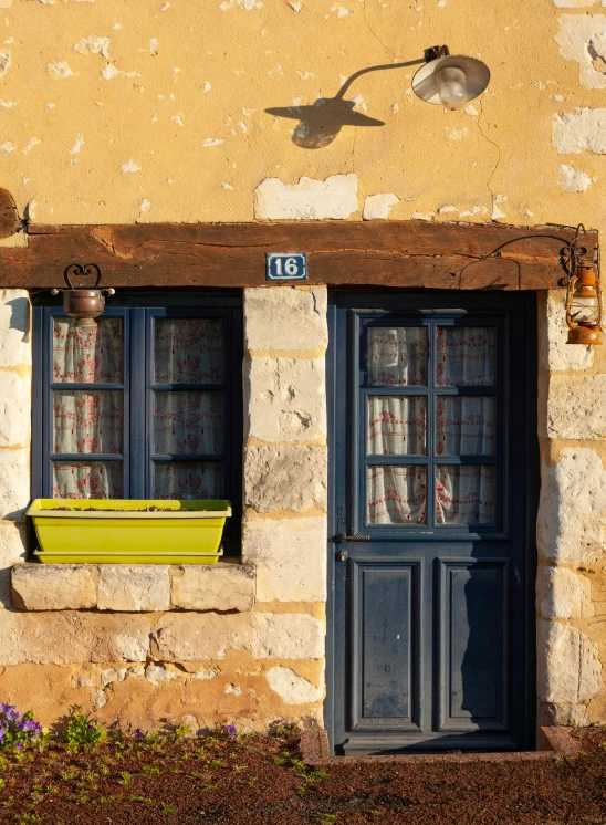 a stone building with blue windows and a yellow planter