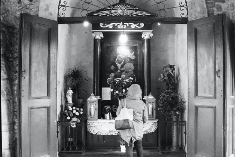 a woman in a coat stands inside of a room