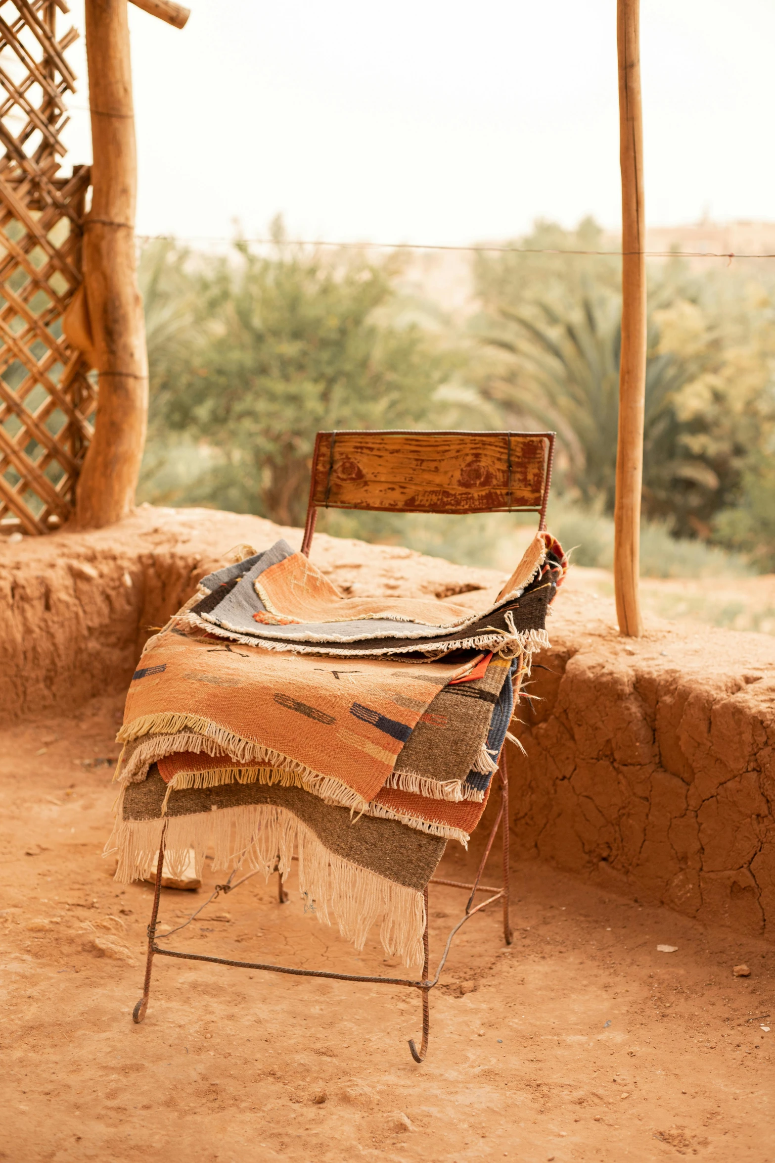 a chair sits in front of a wall covered with woven blankets